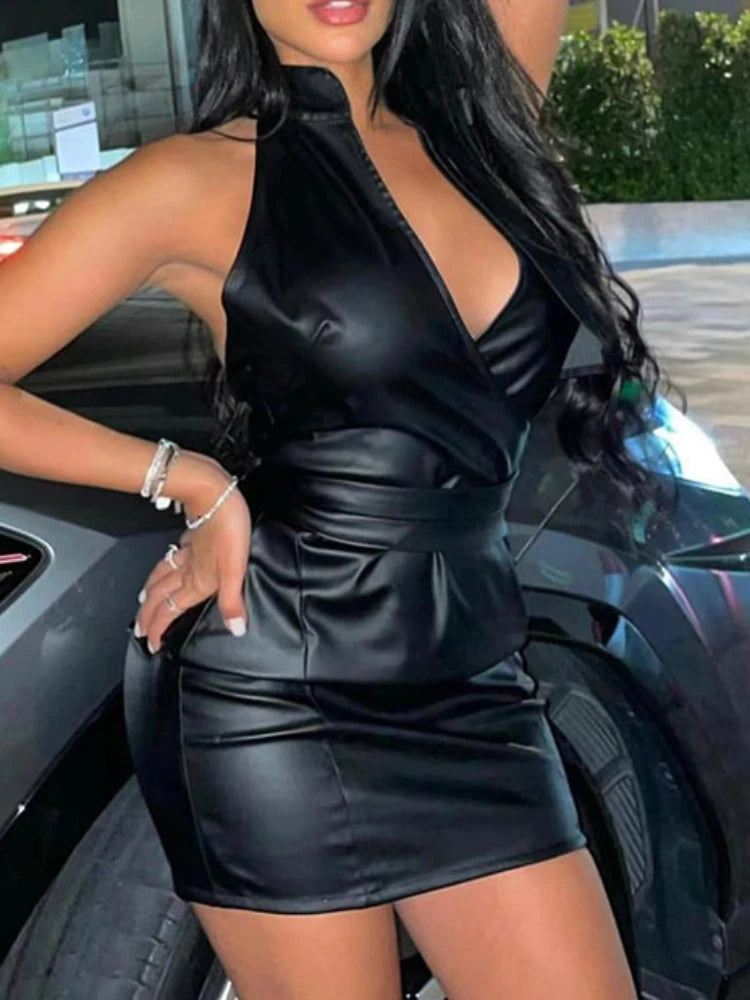 Vestida com o Vestido de Noite Clube Festa da Selluve, um minivestido de couro preto elegante, alguém posa confiantemente perto de um carro. O vestido de couro PU apresenta um decote halter, decote profundo e design sem costas. Seus cabelos longos e ondulados caem em cascata sobre os ombros com pulseiras adicionando charme ao pulso.