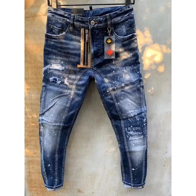 Um par de jeans Dsq2 Itália azul desgastado da Selluve está pendurado em um cabide, exibindo um corte skinny com remendos desbotados, detalhes rasgados e uma etiqueta decorativa perto da cintura. Sombras de folhas e luz do sol criam um estilo único no fundo.