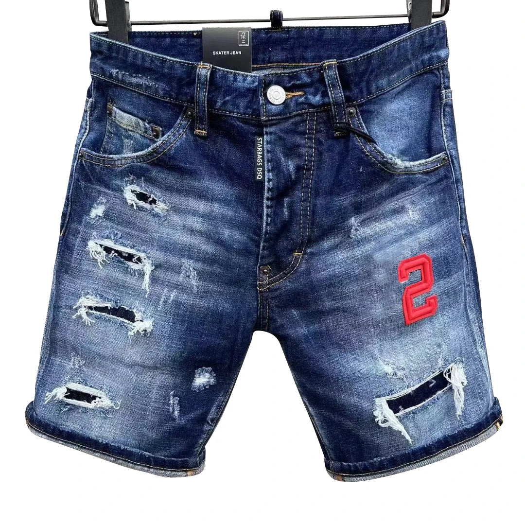O Selluve starbags dsq D301 New apresenta shorts jeans azul desgastado em um ajuste fino, estilo rasgado com furos desfiados e um número vermelho 2 costurado na coxa direita. Com bolsos frontais e traseiros, passadores de cinto e fecho de botão, esses shorts estilosos são exibidos em um cabide.